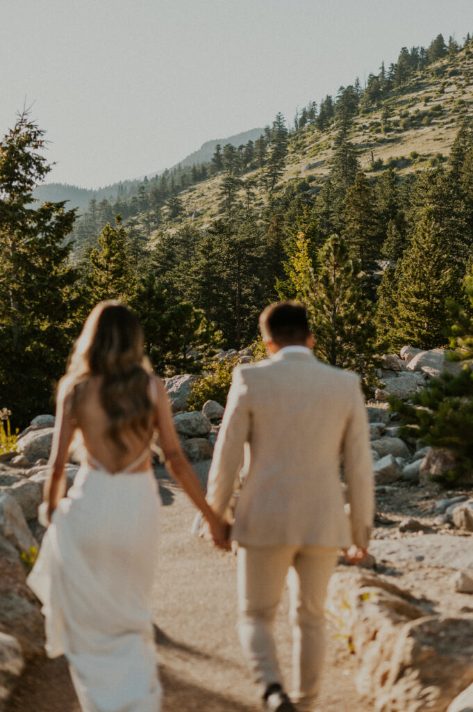 Couple holding hands and walking to their Rocky Mountain National Park Ceremony location. 