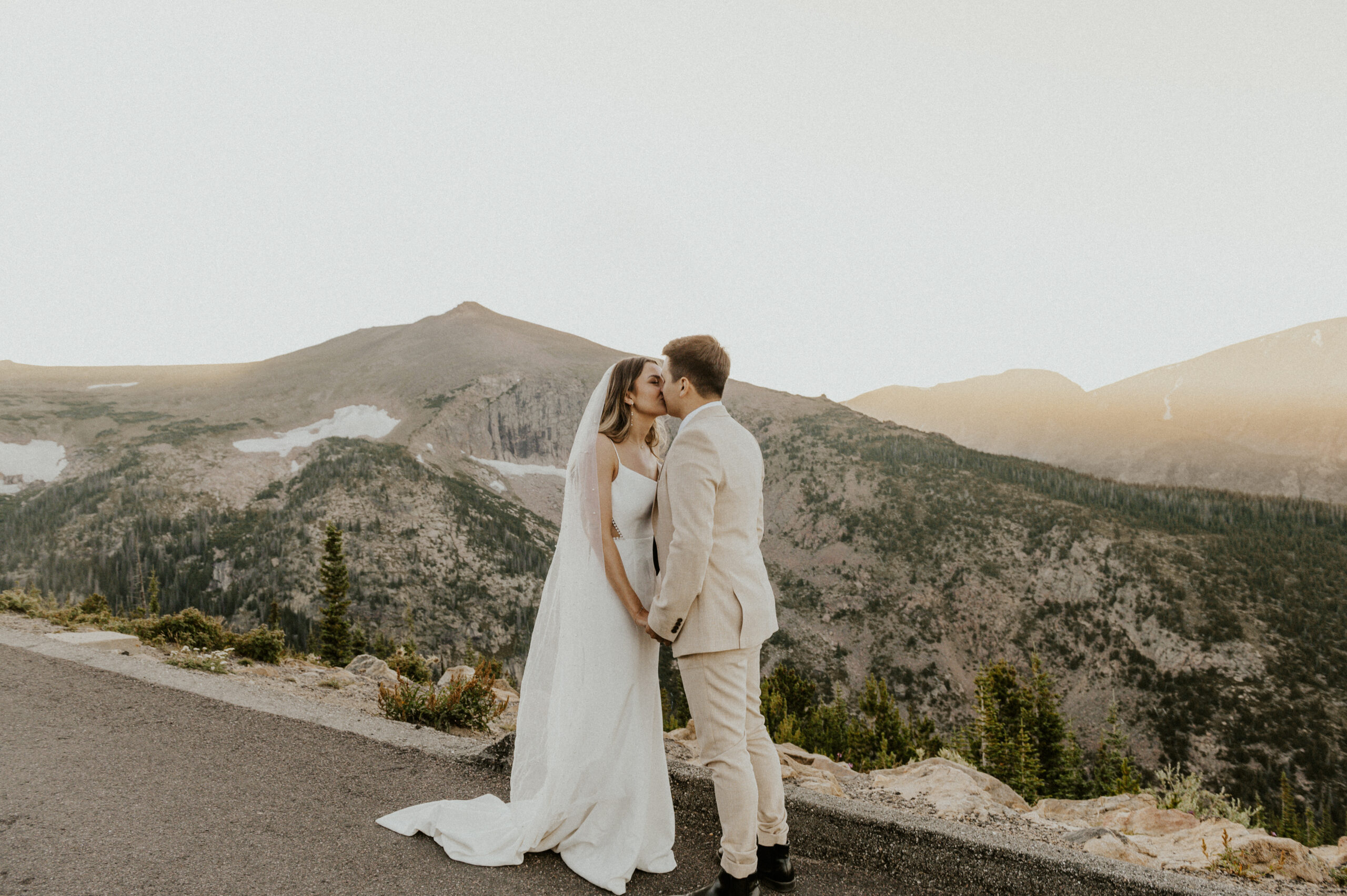 Sunset elopement in Rocky Mountain National Park. Couple in wedding attire kissing.