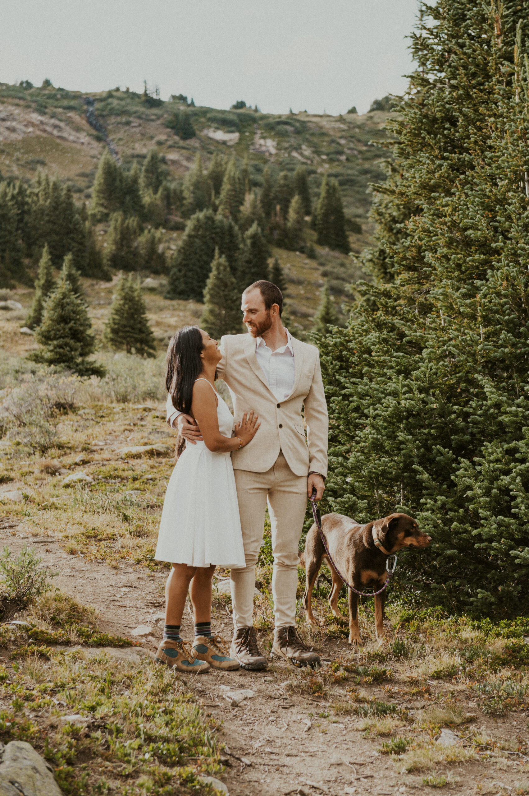 Couple embracing in the forest and holding their dog during their dog-friendly Colorado elopement.