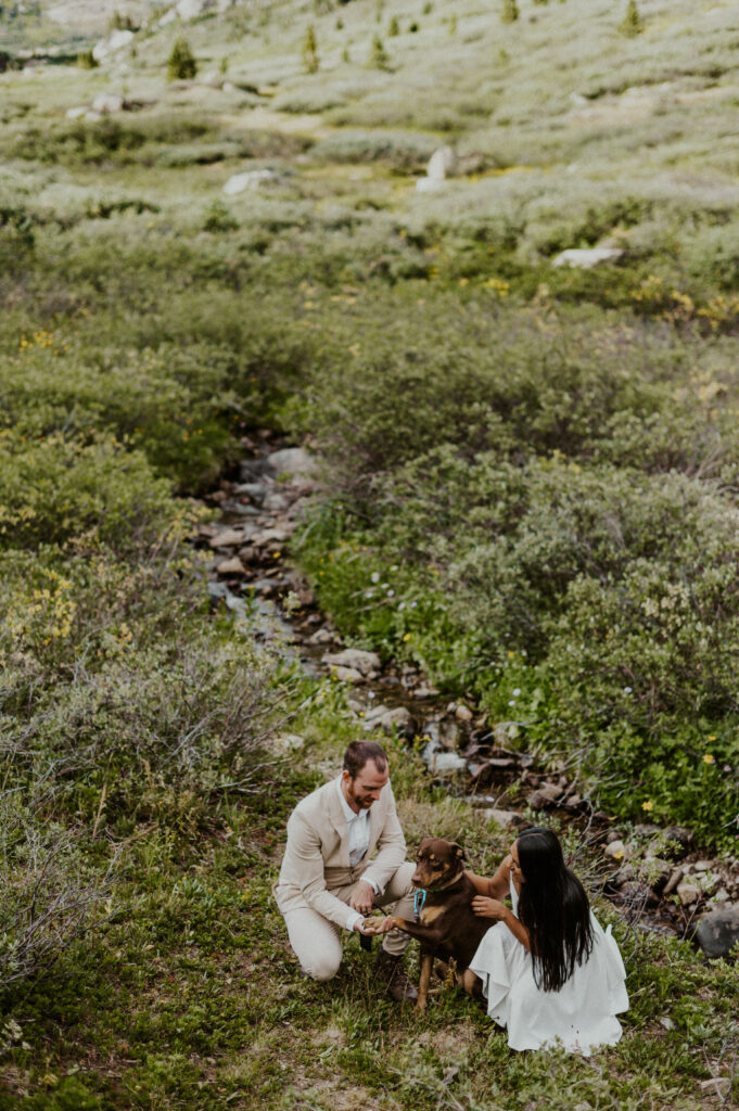 Couple petting their dog on a dog-friendly trail during their Aspen elopement. 