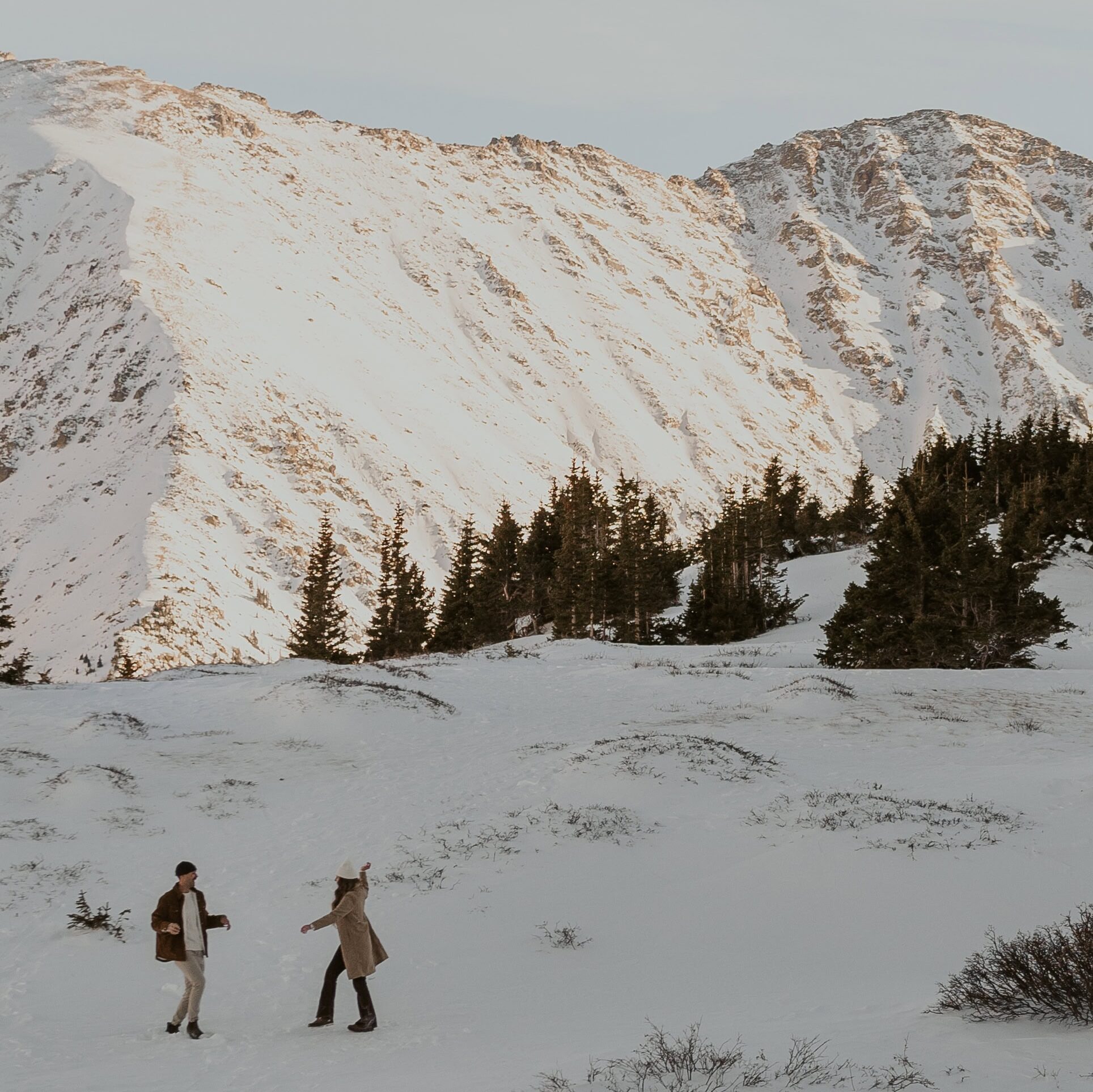 Two people having a snowball fight in the mountains of Breckenridge before their winter elopement in Colorado.