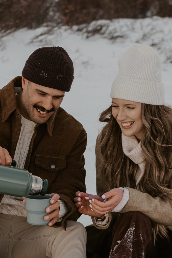 Couple pouring hot cocoa in the snow during their Breckenridge elopement in Winter. 