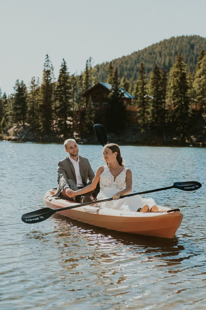Couple holding hands on a kayak in wedding attire during their elopement.