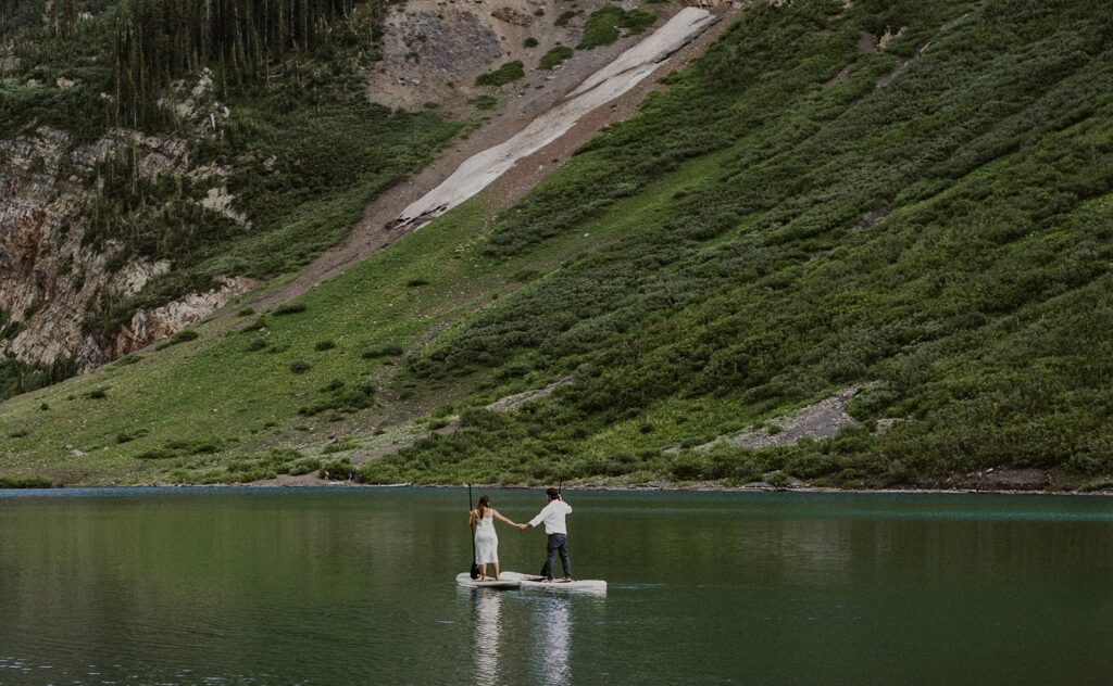 Couple paddle-boarding on an alpine lake during their San Juan Mountains elopement.