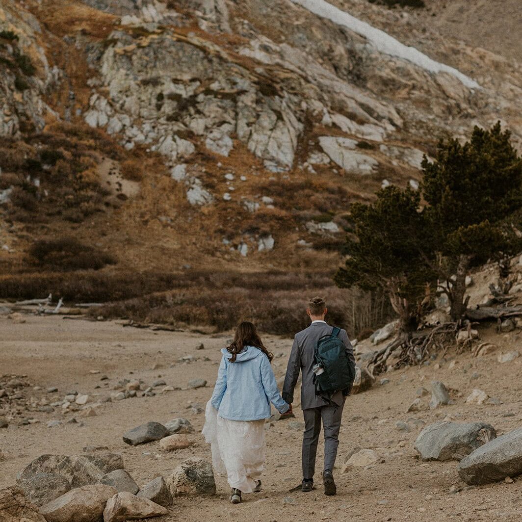 Couple that eloped in the San Juan Mountains hiking up a trail during fall with backpacks.