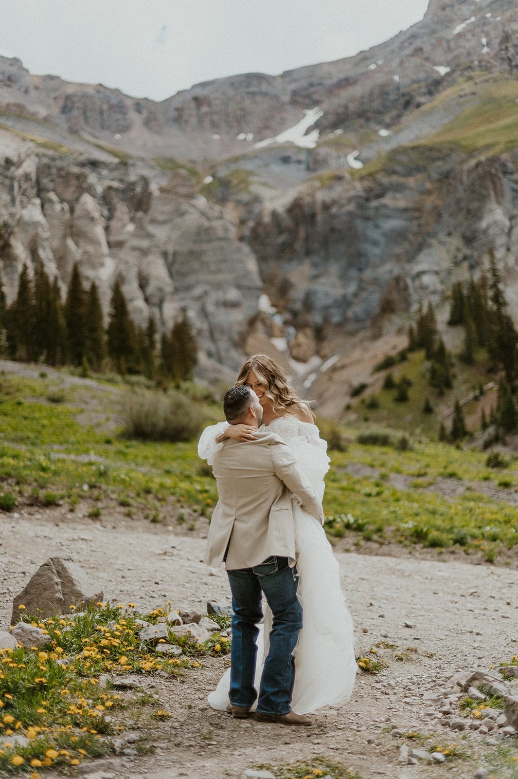 Groom picking up bride with the mountains in the background after their Ouray elopement.